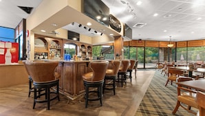 A bar area with a counter, stools, and a view through large windows. - Golf Lover's Paradise with Onsite Course, Games & $400 Daily Tickets Near Silver Dollar City (Reeds Spring)