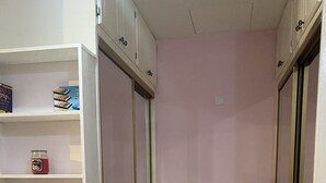 Een kamer met een witte kast, een roze muur en betegelde vloer.