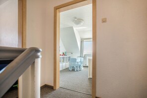 Une pièce avec un plafond en pente, un coin repas avec des chaises et une table, et un radiateur apparent.