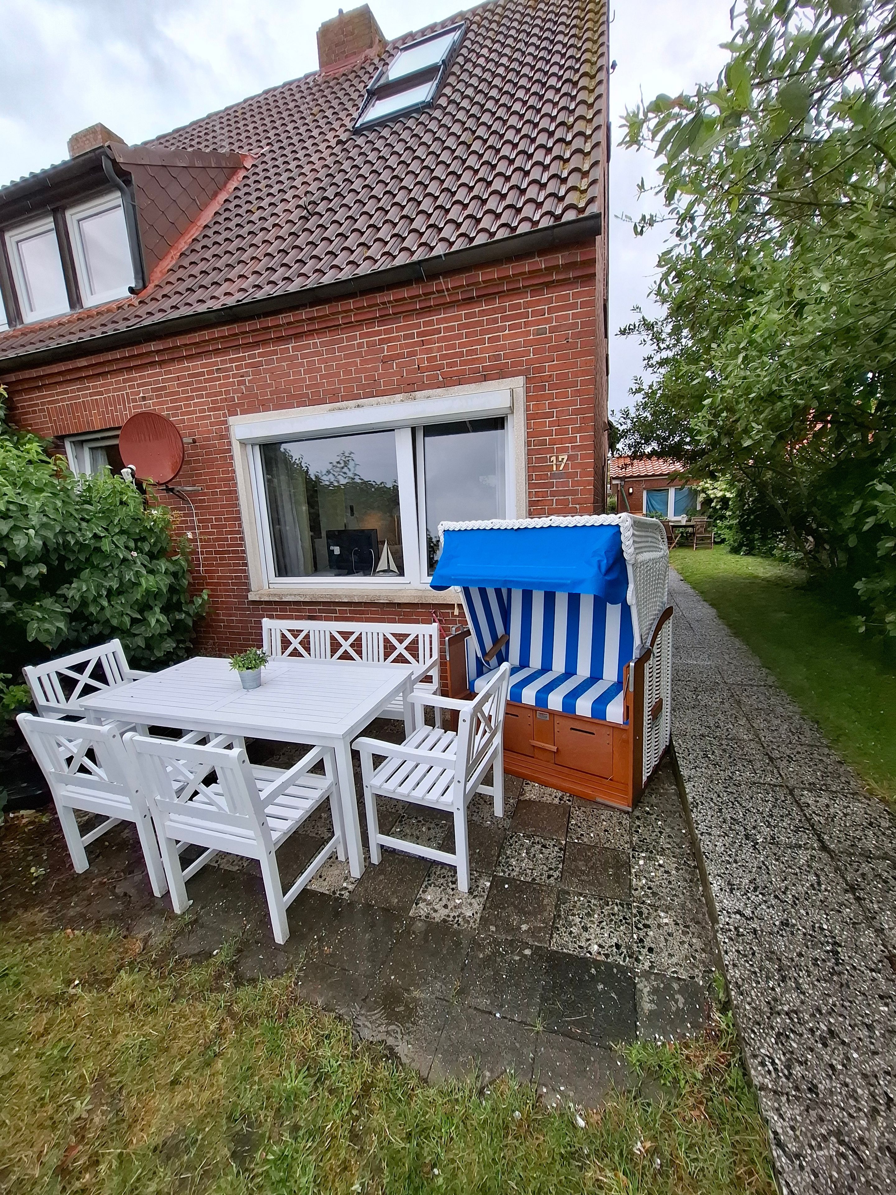 Une maison en briques avec un toit en tuiles, une fenêtre blanche et un patio aménagé avec une table et des chaises.