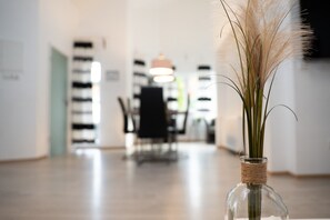 Un intérieur moderne offrant une vue dégagée sur un espace repas, agrémenté d’un vase contenant des plumes d’herbe des pampas et doté d’un plancher en bois.