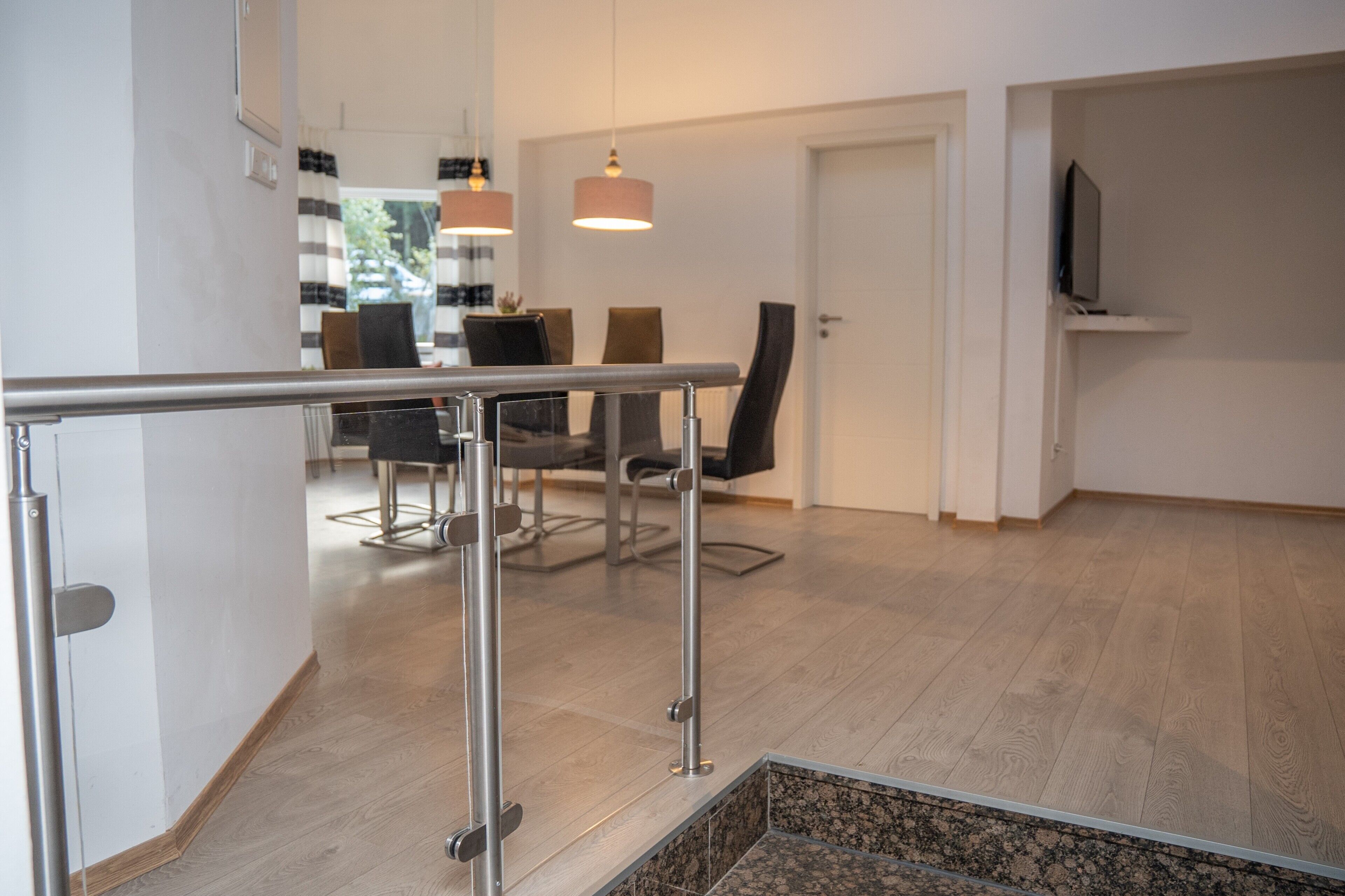 Ein modernes Interieur mit Essbereich, Treppe und an der Wand befestigtem Fernseher.