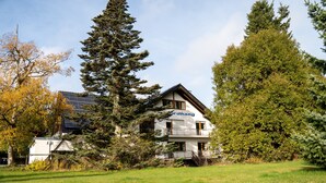 A two-story building with a visible name 'Herdhang' on the facade, surrounded by trees and a grassy area.