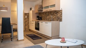 Une cuisine compacte dotée de meubles en bois, d’un four à micro-ondes, d’une machine à café et d’un coin repas avec une table et une chaise.