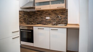 A modern kitchen with white cabinets, a brick backsplash, stainless steel appliances, and a double sink. - 'Villa Nordhang - Apartment 7' with Mountain View, Balcony & Wi-Fi (Winterberg)
