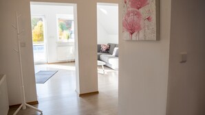 A modern interior with a wooden floor, a white radiator, and a painting of pink flowers on the wall. - 'Villa Nordhang - Apartment 8' with Mountain View, Balcony & Wi-Fi (Winterberg)