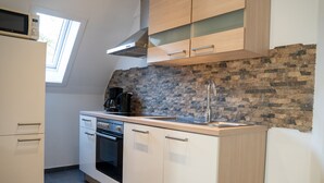 A kitchen with a stone backsplash, a microwave, a stove, and a sink. - 'Villa Nordhang - Apartment 8' with Mountain View, Balcony & Wi-Fi (Winterberg)
