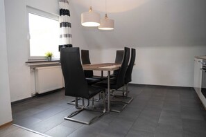 Un comedor moderno con una mesa rectangular, sillas negras e iluminación colgante.