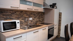 Cocina moderna con microondas, fregadero, horno y encimera de madera.