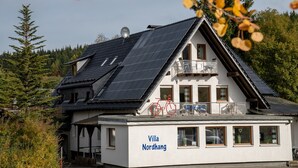 A building with solar panels, a balcony, and the name 'Villa Nordhang' on the side.
