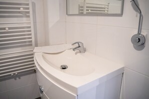 A bathroom with a white sink, a mirror, and a towel rack. - 'Villa Nordhang - Apartment 14' with Mountain View & Wi-Fi (Winterberg)