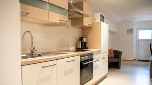 A modern kitchen with a stainless steel sink, a coffee maker, and a built-in oven.