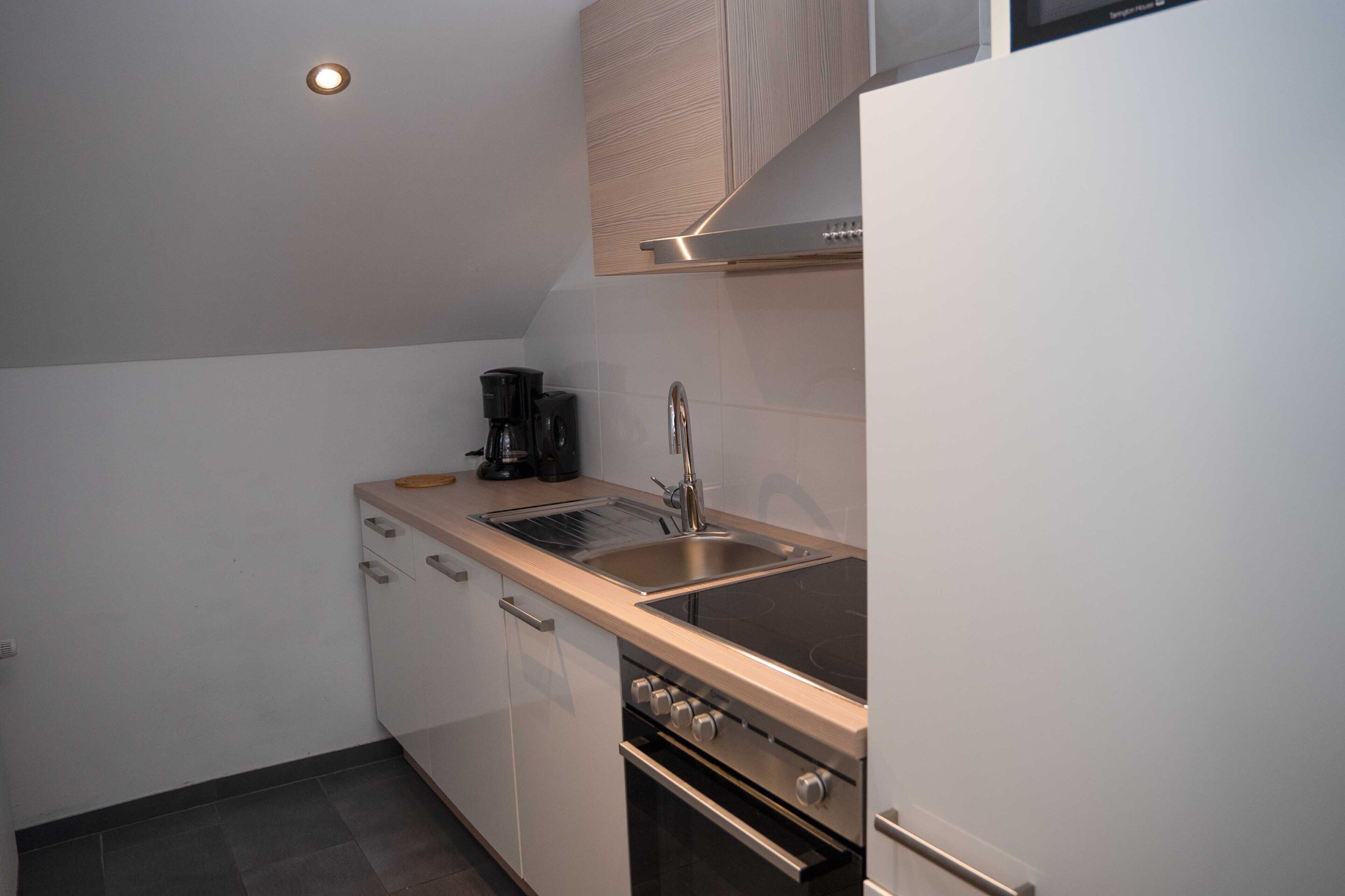 Una cocina compacta con fregadero, estufa y armarios.