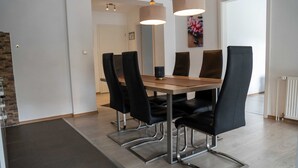 Comedor con una mesa de madera, sillas negras y lámparas colgantes.