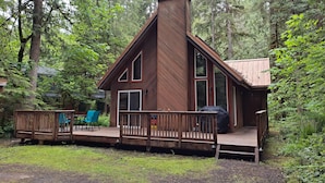 Eine Holzhütte mit einer Holzterrasse, großen Fenstern und einem Schornstein.