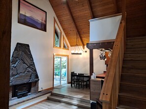 A wooden interior with a stone fireplace, a dining area, and a staircase. - Mt cabin in private community close to Mt Baker (Deming)