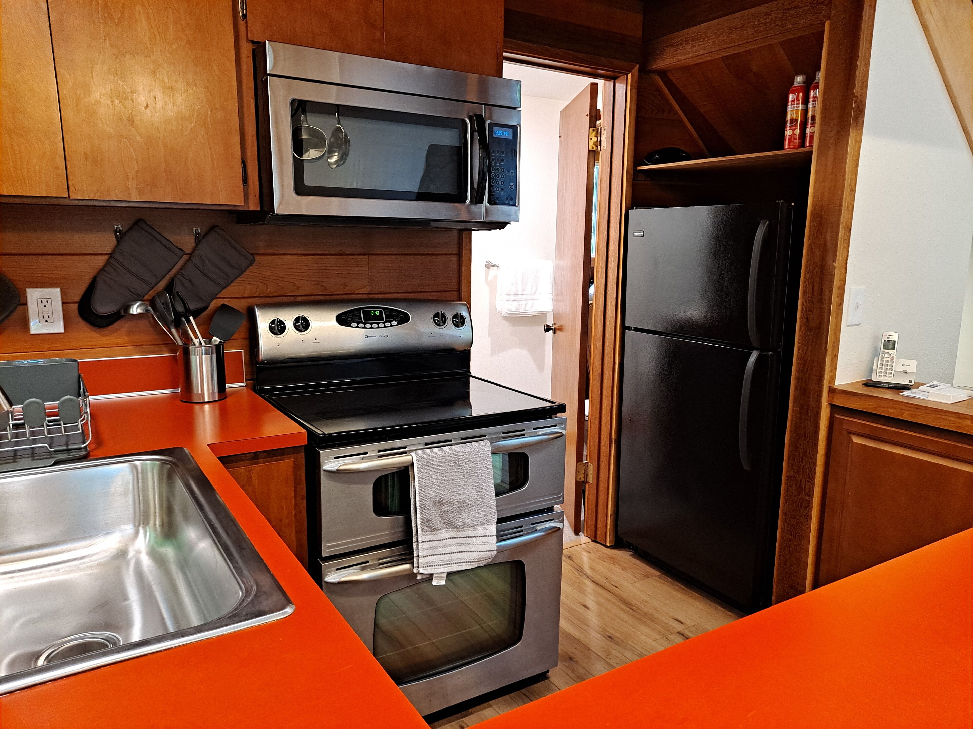 A compact kitchen with a microwave, oven, and refrigerator.
