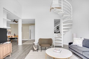 Relax in this stylish living space with a spiral staircase, flat-screen TV, and comfortable sofa.