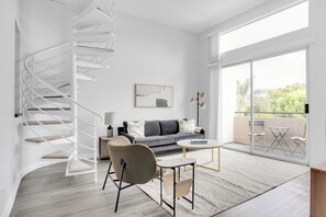 Relax in this inviting living space with a spiral staircase, grey sofa, and comfortable armchair.