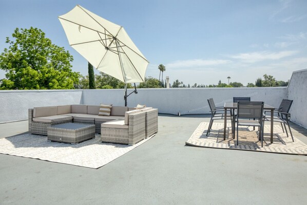 Relax in a spacious outdoor seating area with a sectional sofa, dining table, and umbrella.