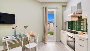 A modern kitchen with a built-in oven, a dining area with a table and chairs, and a TV mounted on the wall. - Eclisse House Few Steps From The Sea, Augusta, Italy (Augusta)