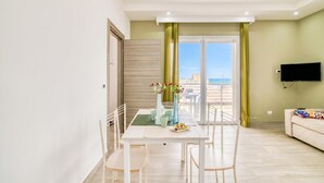 Un salon moderne comprenant un coin repas, un téléviseur à écran plat fixé au mur et une vue sur l’extérieur.
