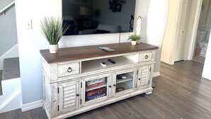 A wooden entertainment center with a flat-screen TV, two potted plants, and a remote control. - Beach House ∆ Prime Location ∆ Steps to the Ocean (Old Orchard Beach)