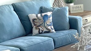 A blue sofa with a decorative pillow, a lamp, a plant, and a sign with the number 04064. - Beach House ∆ Prime Location ∆ Steps to the Ocean (Old Orchard Beach)