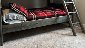 A bunk bed with a wooden ladder, a plaid blanket, and pillows. - 🇨🇦 Lake Winnipeg Fishing All-Seasonal Retreat (Winnipeg Beach)