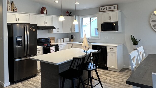 A modern kitchen with a central island, black chairs, and a dining table. - 🇨🇦 Lake Winnipeg Fishing All-Seasonal Retreat (Winnipeg Beach)