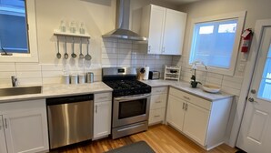 Een moderne keuken met roestvrijstalen apparatuur, witte keukenkastjes en een houten vloer.