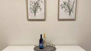 Een witte kast met drie lades, een wijnrek, een fles wijn en twee glazen op een dienblad.