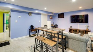 Ein modernes Wohnzimmer mit Essbereich, ausgestattet mit einer Couch, einem Couchtisch und einem an der Wand montierten Fernseher.