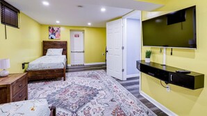 Ein Schlafzimmer mit Bett, Nachttisch, Lampe und einem an der Wand montierten Fernseher.