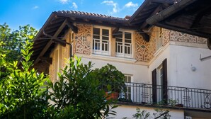 A building with a tiled roof, decorative facade, and a balcony with a wrought iron railing. - Piccolo Mondo Antico: Stresa 2BR Apartment with Lake View, Stresa, Italy (Stresa)