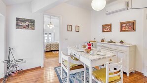 A dining area with a white table, chairs, and a hanging light fixture. - Piccolo Mondo Antico: Stresa 2BR Apartment with Lake View, Stresa, Italy (Stresa)