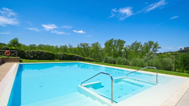 A rectangular swimming pool with clear blue water, surrounded by a paved deck and a grassy area with trees. - Francigena 5, Castelfiorentino, Italy (Castelfiorentino)