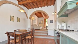 A kitchen with a wooden table and chairs, a stove, and a tiled backsplash. - Francigena 5, Castelfiorentino, Italy (Castelfiorentino)