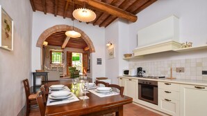 A kitchen with a wooden table set for dining, a microwave, and a stove.