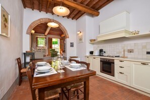 A kitchen with a wooden table set for dining, a microwave, and a stove. - Francigena 4, Castelfiorentino, Italy (Castelfiorentino)