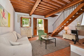 A living room with a sofa, a green armchair, a coffee table, a cabinet, a lamp, and a staircase. - Francigena 4, Castelfiorentino, Italy (Castelfiorentino)