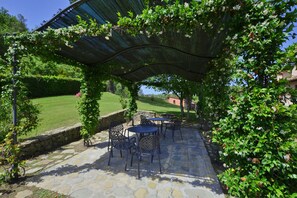 Relax in a serene outdoor seating area surrounded by lush greenery and a stone wall.
