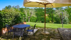 An outdoor patio with a table and chairs, a large umbrella, and a stone pathway. - Francigena 4, Castelfiorentino, Italy (Castelfiorentino)