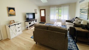 A living room with a sofa, TV, and artwork on the walls.