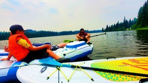 A group of people on inflatable kayaks on a calm lake with trees in the background. - Spacious Lakefront Campsites (Lone Butte)