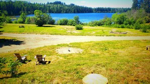 A grassy area with a wooden stump, two wooden chairs, and a picnic table. - Spacious Lakefront Campsites (Lone Butte)