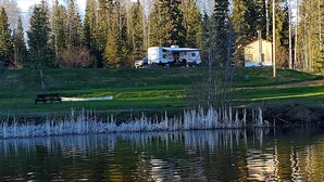 A lakeside RV campsite with a picnic table and a cabin in the background. - Spacious Lakefront Campsites (Lone Butte)