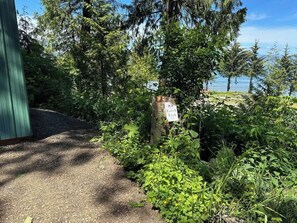 A gravel path leading to a wooden structure with a sign reading "Earth Trek." - A-Frame Shelter (T15)  - Oceanside Views (Port Angeles)