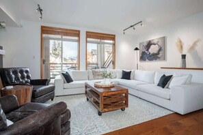 Una sala de estar moderna con un sofá blanco, un sillón de cuero y una mesa de centro de madera.