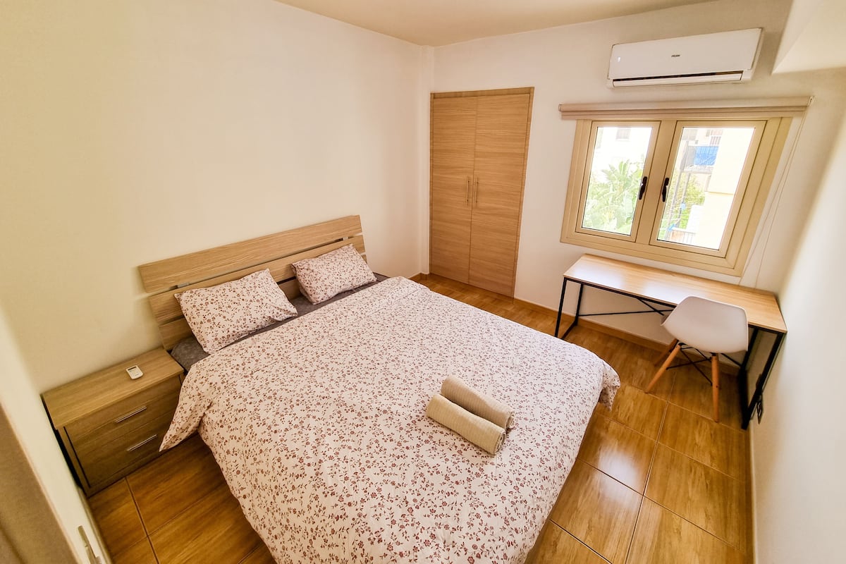 A bedroom with a bed, a desk, and a wardrobe.